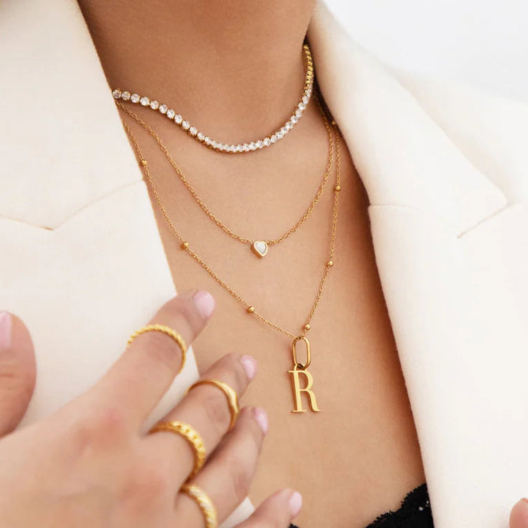 Person wearing multiple gold necklaces and rings on a white background