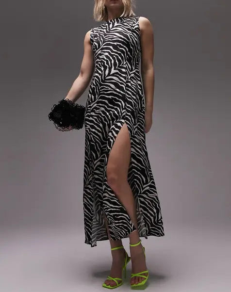 Woman wearing a zebra print dress with a high slit on a gray background